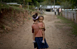 A young girl carries her brother to the water well in Maubara. Photo by UNMIT/Bernardino Soares